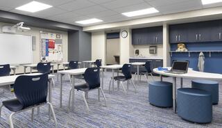 A modern classroom features blue chairs, white tables, a projector, a clock, and a bulletin board, creating an inviting learning space.