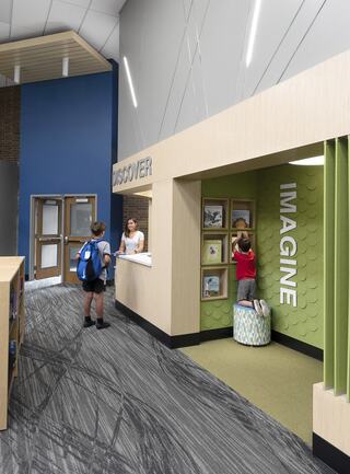 A bright, modern space features interactive areas labeled "Discover" and "Imagine." Children engage with displays while an adult assists at the counter.