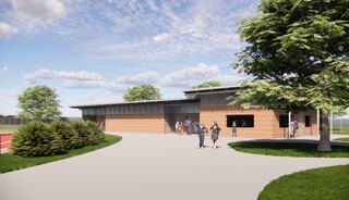 A modern, brick-clad building with large windows, surrounded by greenery, featuring a light pathway and people engaging outside.