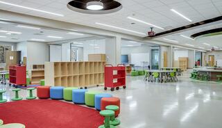 A bright, modern classroom features colorful seating, organized shelves, interactive areas, and a spacious layout designed for learning.