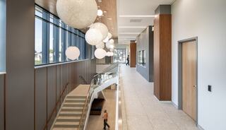 A spacious hallway features large, decorative light fixtures, large windows, and a staircase, creating a bright and modern atmosphere.