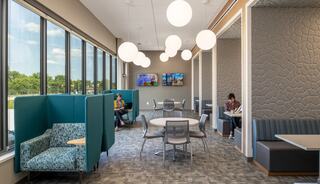 A bright, modern lounge with large windows, stylish seating, and soft lighting, creating a comfortable space for relaxation and socializing.