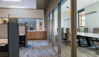 A modern office space featuring glass-walled meeting rooms, a spacious layout, and stylish furnishings, promoting collaboration and efficiency.