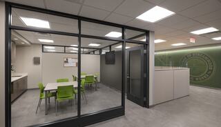 A modern meeting room features a white table surrounded by green chairs, sleek walls, and large windows, promoting a collaborative atmosphere.