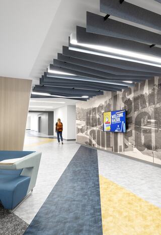 A modern hallway features unique ceiling designs, colorful flooring, and a welcoming digital display, creating an inviting atmosphere.