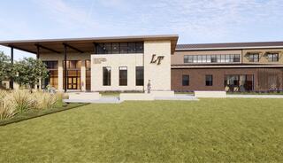 A modern building features a stylish entrance with large windows, landscaped greenery, and a welcoming façade showcasing "LT."