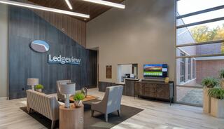 A modern, inviting lobby with a wooden accent wall, comfortable seating, and a welcoming reception area featuring a logo and digital display.
