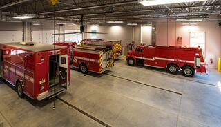 A modern fire station interior showcases several red emergency vehicles parked in spacious bays, ready for action.