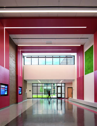 A modern, spacious hallway features pink walls, large windows, and stylish lighting, creating a bright and inviting atmosphere.