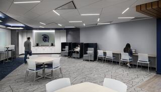 A modern study space featuring sleek furniture, workstations, and a calming color palette, with individuals engaged in various activities.