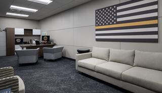 A modern office space features a sofa, armchairs, and a desk with a wall displaying a stylized American flag.