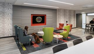 A cozy lounge features colorful chairs, a coffee table, and a woman petting a dog, creating a welcoming atmosphere for relaxation.