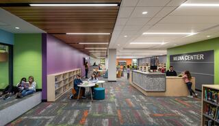 A vibrant media center featuring colorful walls, diverse seating areas, and shelves filled with books, fostering a collaborative learning environment.