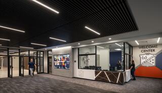 A modern welcome center features sleek design, a reception area, and a large display screen, creating a welcoming atmosphere.