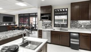 A modern kitchen features dark cabinetry, stainless appliances, and a stylish backsplash, with a spacious layout and dining area visible.