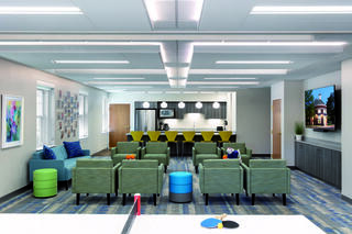 Youth room at Lewinsville Presbyterian Church, featuring a mix of comfortable seating and lounge options, a kitchen with countertop seating, a wall mounted tv and a ping pong table.