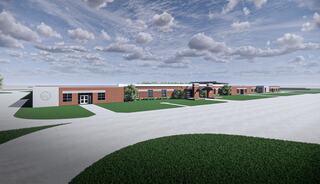 A modern school building features red brick and large windows, surrounded by green lawns and a clear sky with scattered clouds.