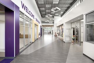 A modern, spacious hallway features welcoming signage, large windows, and children engaged in activities, showcasing a vibrant atmosphere.