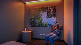 A person sits in a cozy, softly lit room with a nature-themed wall art, creating a serene and relaxing atmosphere.