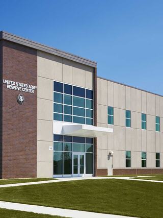 A modern building features large windows and a prominent entrance, showcasing the United States Army Reserve Center against a clear blue sky.