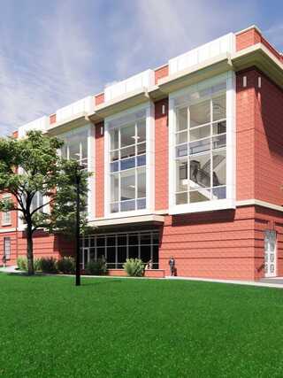 A modern brick building with large windows, surrounded by greenery and a tree, exuding a welcoming and contemporary atmosphere.