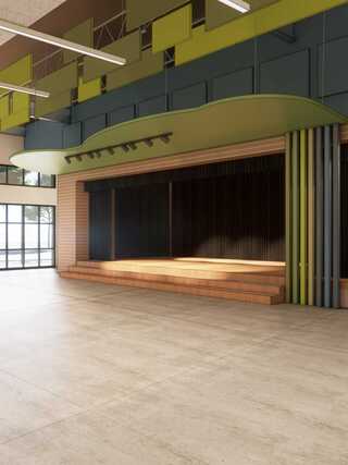 Spacious indoor area featuring a wooden stage, modern green accents, and ample natural light from large windows.