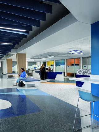 A modern, open space featuring sleek design, vibrant colors, and seating areas. People engage at service counters in a welcoming environment.