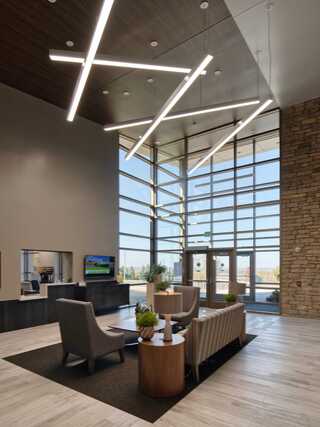 A modern lobby features sleek furniture, geometric lighting, and large windows, creating an inviting and bright atmosphere.