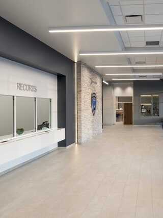A modern, spacious reception area featuring a service counter labeled "RECORDS," with stylish lighting and a stone accent wall.