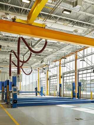 Bright workshop with high ceilings, large windows, and overhead cranes. Equipped with blue work platforms and ventilation systems.