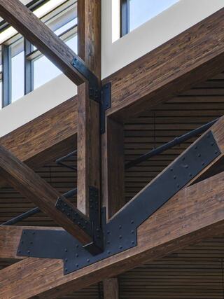 A close-up view of wooden beams intersected by metal brackets, showcasing an industrial design with a blend of natural and modern elements.