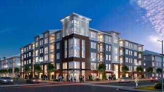 A modern, multi-story apartment building with large windows and stylish design, illuminated at dusk, featuring pedestrians and vehicles nearby.