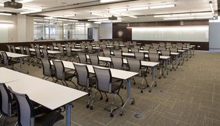 A modern classroom features neatly arranged tables and chairs, with a sleek design and ample lighting, creating an inviting learning environment.