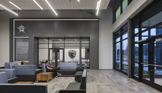 A modern police station lobby features sleek seating and large windows, creating an open, inviting atmosphere for visitors.