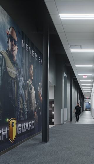 A sleek, modern hallway features a large security-themed mural and a uniformed individual walking toward the end.