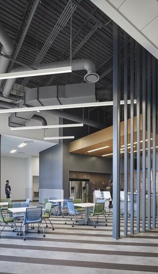 A modern, open kitchen and dining area features sleek furniture and contemporary design elements, with industrial-style lighting and finishes.