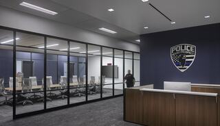 A modern police office features a reception area and a conference room with glass walls, showcasing a professional environment.