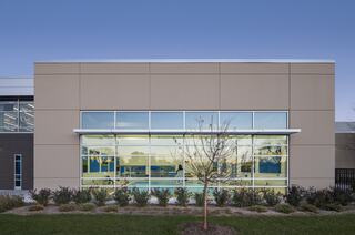 Modern building facade with large windows, surrounded by landscaping and a clear sky in the background, offering a clean, inviting appearance.