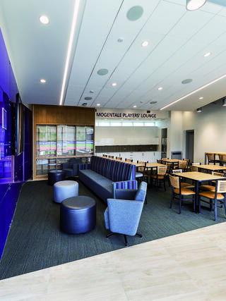 A modern lounge features sleek seating, a large TV, and dining areas, creating a cozy, inviting space for relaxation and socializing.