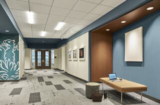 A modern hallway with blue walls, stylish artwork, a bench, and a small table, showcasing a blend of comfort and contemporary design.