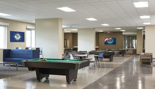 A spacious game room features pool tables, seating areas, and wall decorations, creating a casual and inviting recreational space.