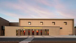 Springman Middle School Exterior Addition at dusk with pink clouds in background, facing an entrance and two-story lobby with high square windows to let light through