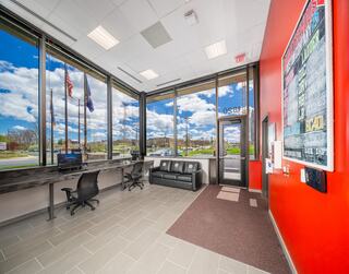 A bright reception area features large windows with a view, a sofa, and a desk with chairs, creating an inviting atmosphere.