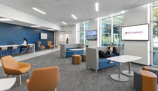 A modern lounge featuring comfortable seating, large windows, and digital displays, promoting a welcoming atmosphere for relaxation or work.