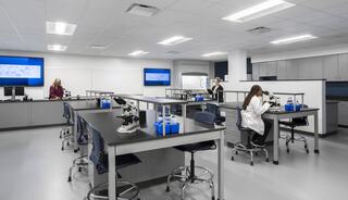 A modern laboratory with sleek desks, microscopes, and digital screens, where individuals are engaged in scientific work and research.