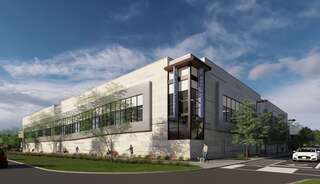 A rec center features large windows and greenery around its perimeter, set against a blue sky with scattered clouds.