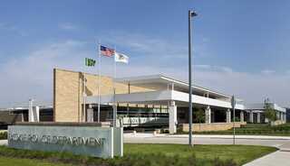 Skokie Police Department, a modern adaptive reuse building featuring contemporary architecture, large windows, and flags displayed outside in a landscaped area.