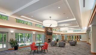 A spacious, modern multi-purpose gathering space features large windows, comfortable seating, and a stone fireplace, creating a welcoming atmosphere.