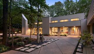 A modern church facility with sleek lines, surrounded by lush greenery and softly lit pathways, creates a tranquil, inviting atmosphere.