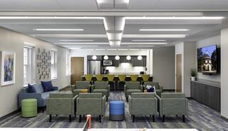 A brightly lit communal space featuring colorful seating, a kitchenette, and large windows, creating a welcoming and modern atmosphere.